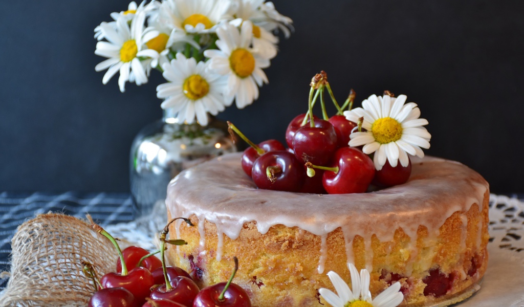 Свежий пирог вишней на столе с ромашками 