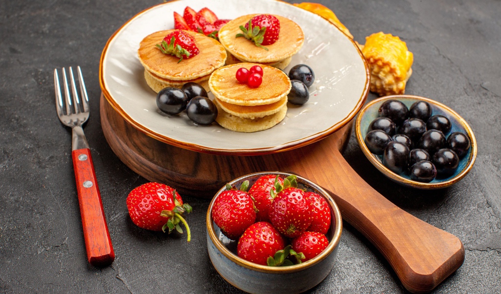 Оладьи с виноградом и клубникой на тарелке 