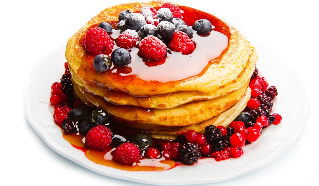 Оладьи с медом и ягодами малины и черники на белом фоне