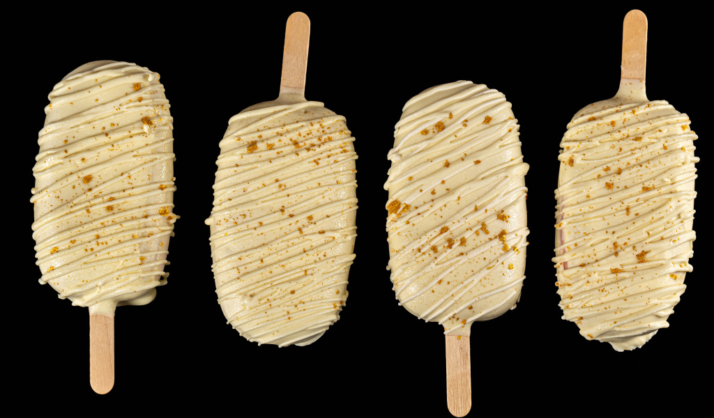 Мороженое на палочке в белом шоколаде на черном фоне