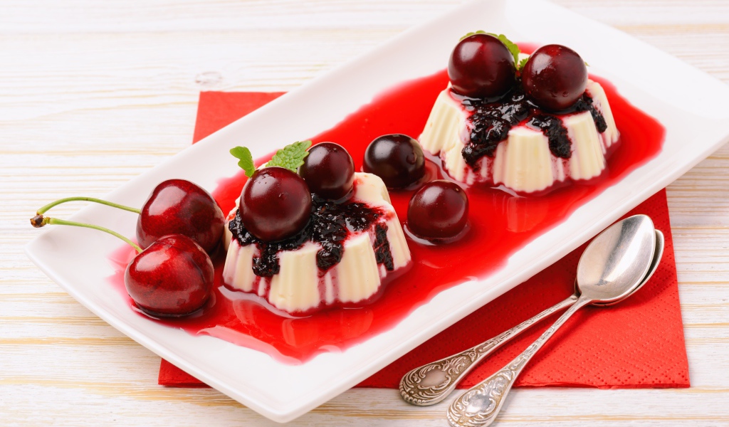 Молочный десерт на тарелке с вишней