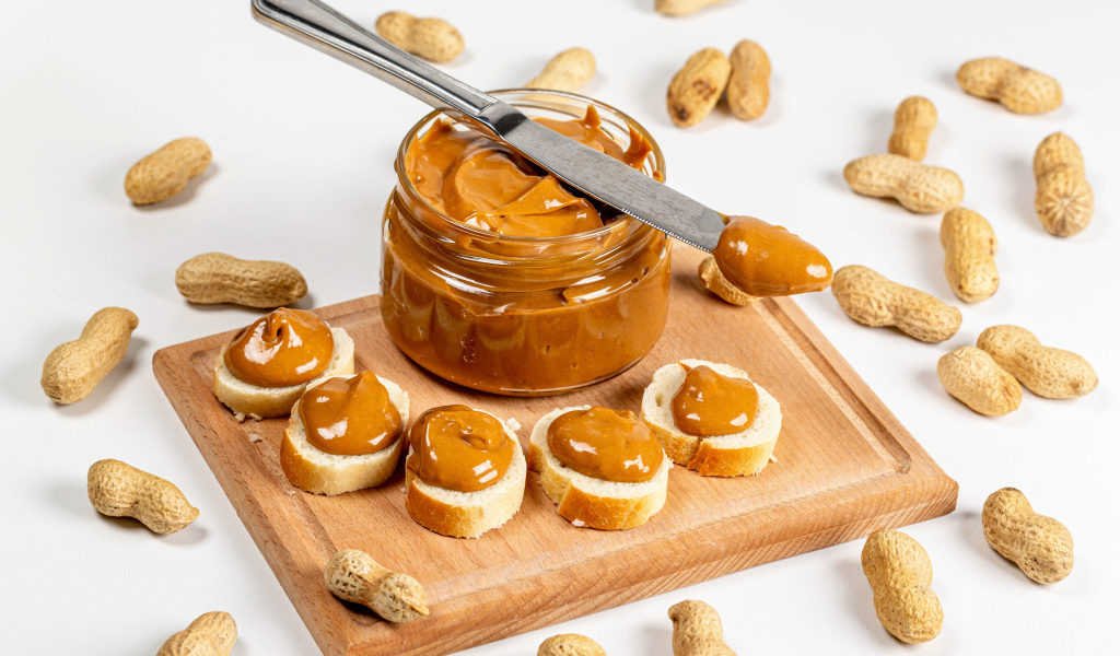 Ореховая паста на столе с батоном и арахисом