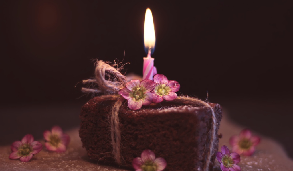 Кусок торта на столе с розовыми цветами и свечкой