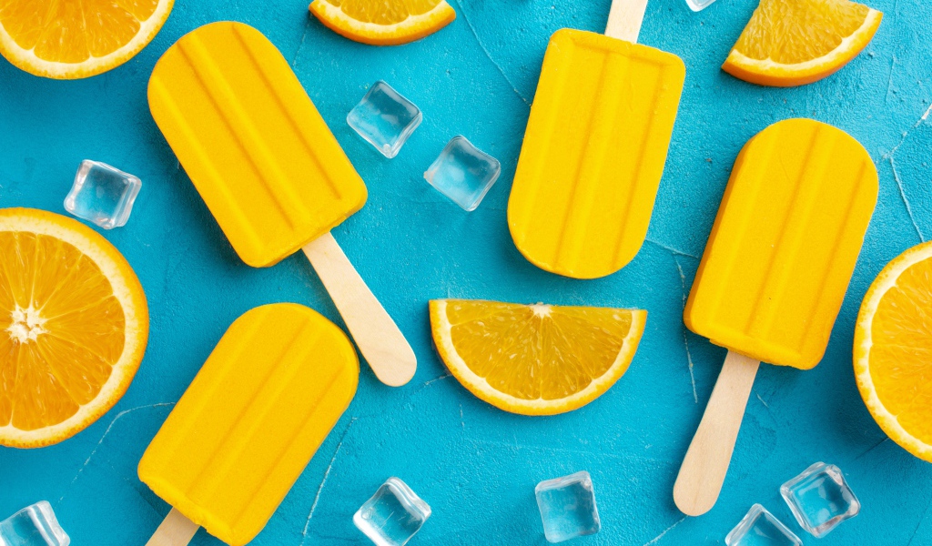 Фруктовое мороженое с кусочками льда и апельсина на голубом столе 