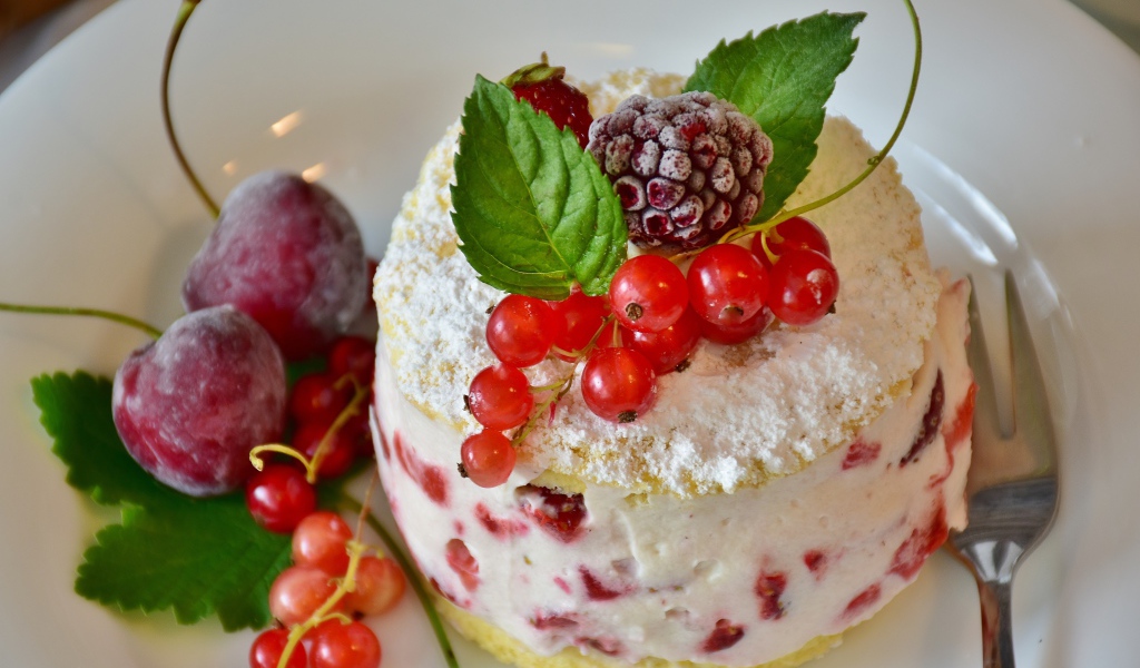 Пирожное со взбитыми сливками украшено ягодами