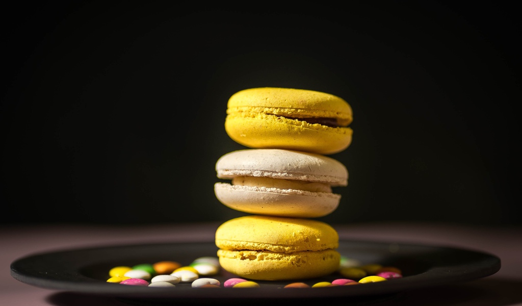 Желтый десерт макарун на тарелке