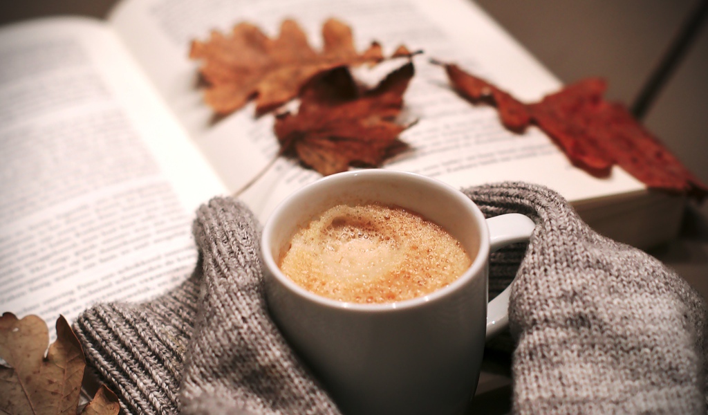 Чашка горячего кофе на столе с книгой 