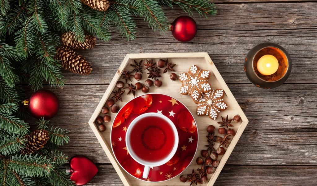 Чашка чая с печеньем и орехами на столе с еловой веткой