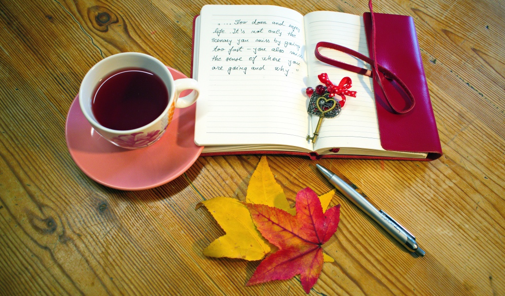 Чашка чая с блокнотом и листьями на столе 