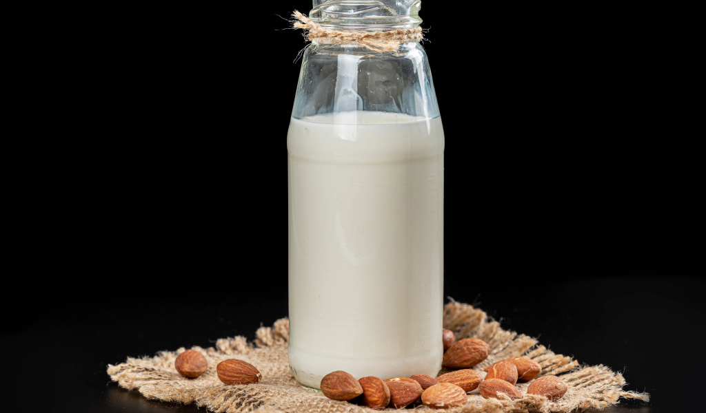 Молоко с миндалем на черном фоне