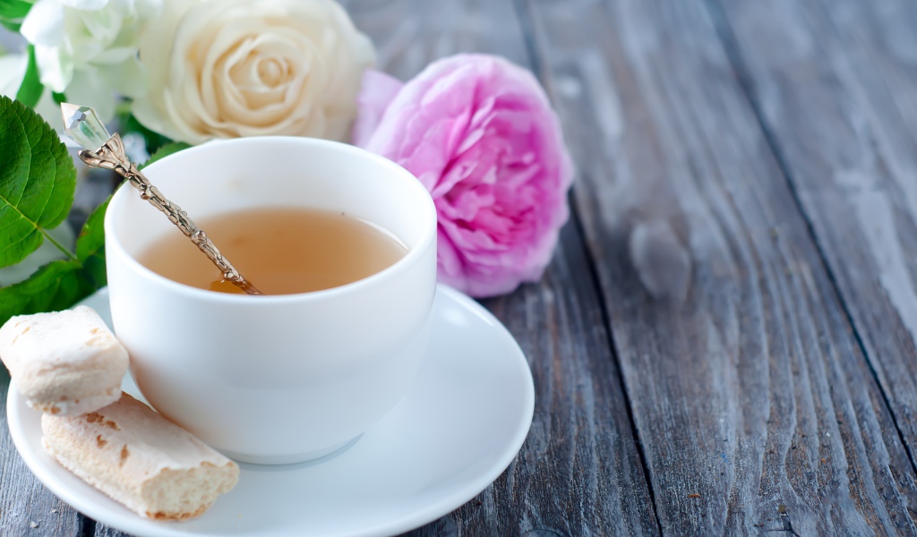 Белая чашка чая на деревянном  столе с розами