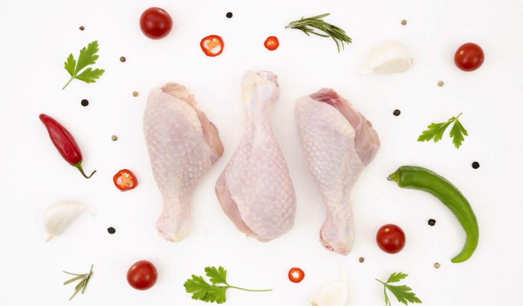 Fresh chicken thighs with peppers and tomatoes on a white background