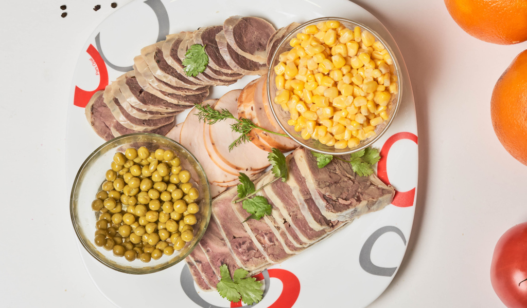 Мясные продукты на тарелке с кукурузой и зеленым горошком 