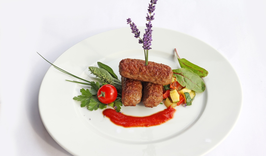 Мясные палочки на тарелке с зеленью и соусом