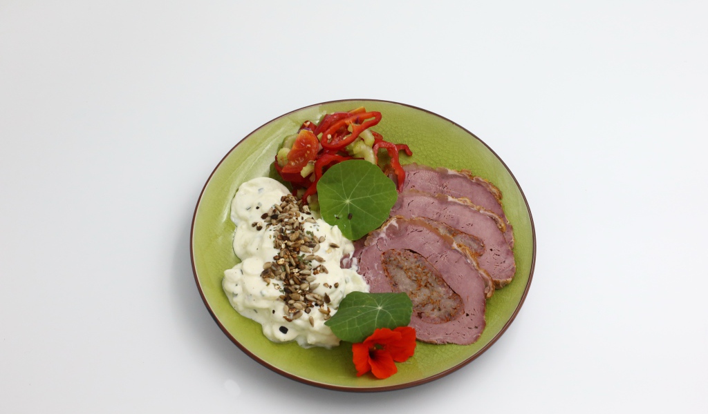 Мясо с соусом и овощами на тарелке на сером фоне