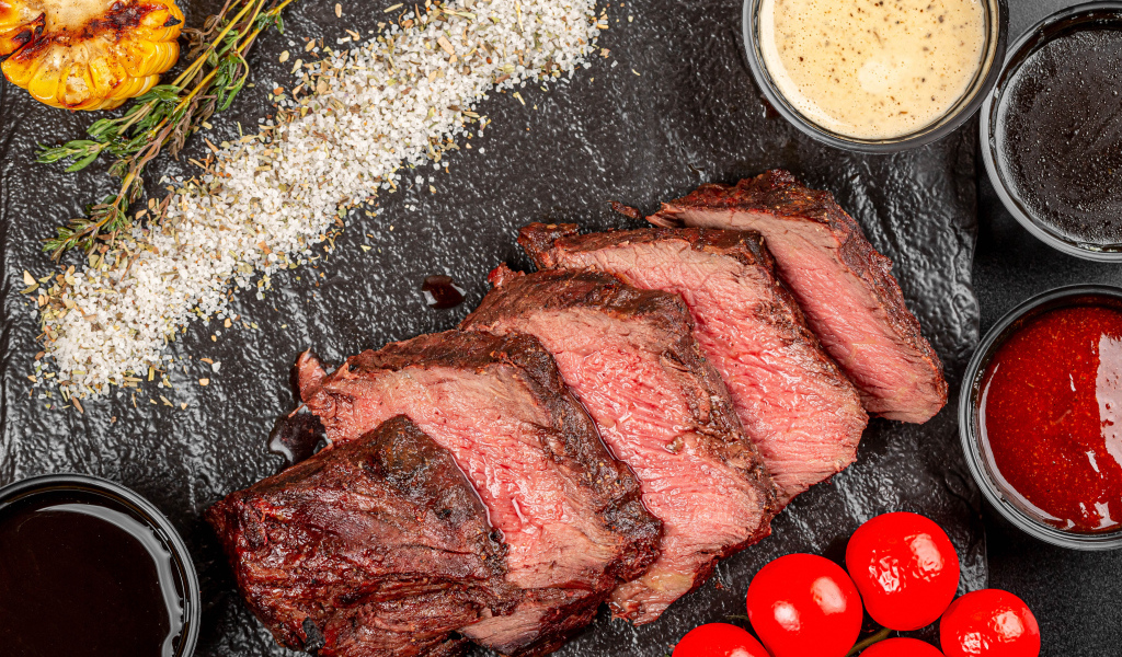 Мясо с помидорами и соусами на доске 