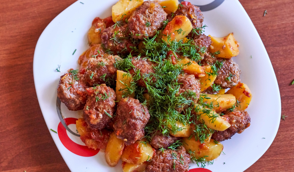 Meatballs with potatoes and dill on a white plate