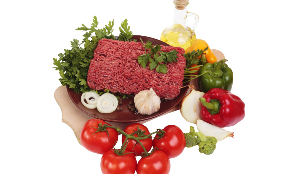 Minced meat on a white plate with vegetables and herbs