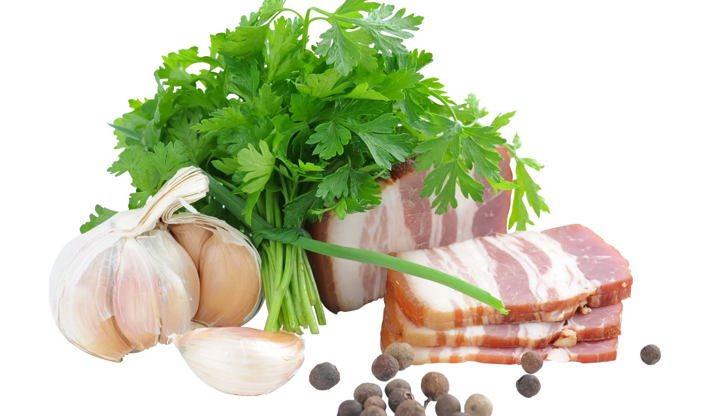 Кусок сала на белом фоне с зеленью петрушки и специями