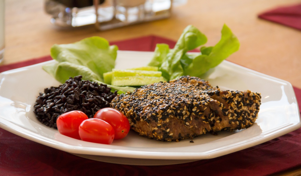 Кусок мяса на тарелке с рисом и овощами 