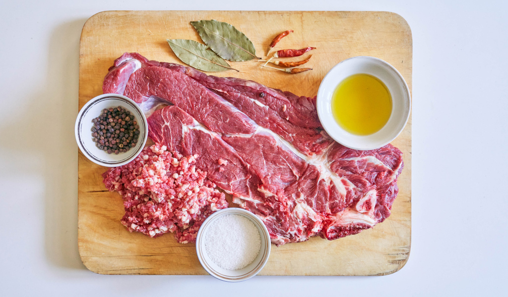 Кусок мяса со специями и оливковым маслом на доске 