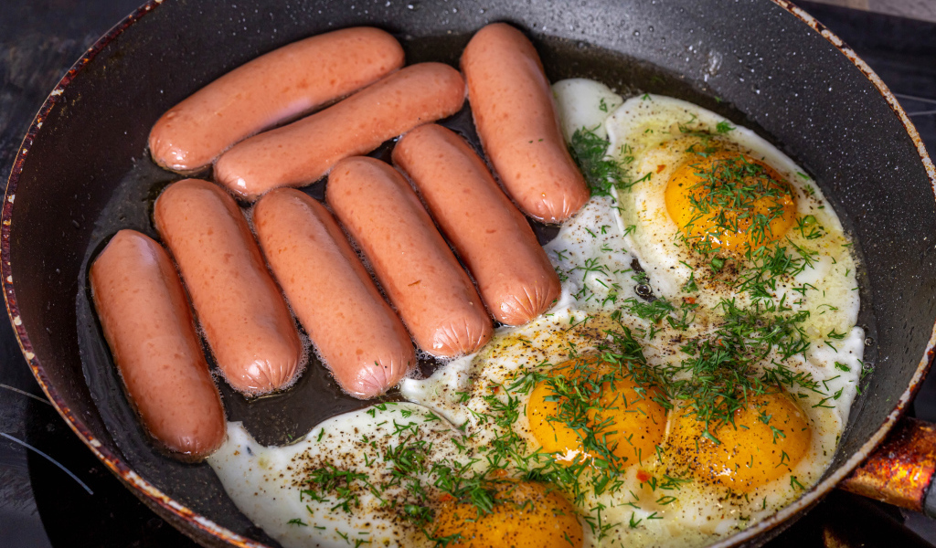 Сосиски с яичницей на сковороде