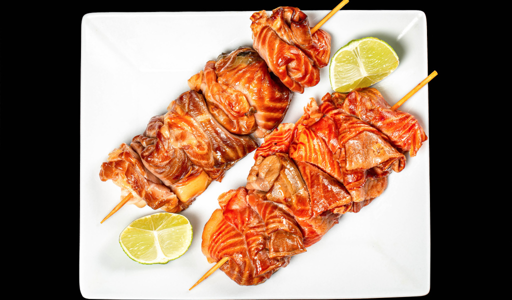 Шашлык на шпажках на белой тарелке с лимоном