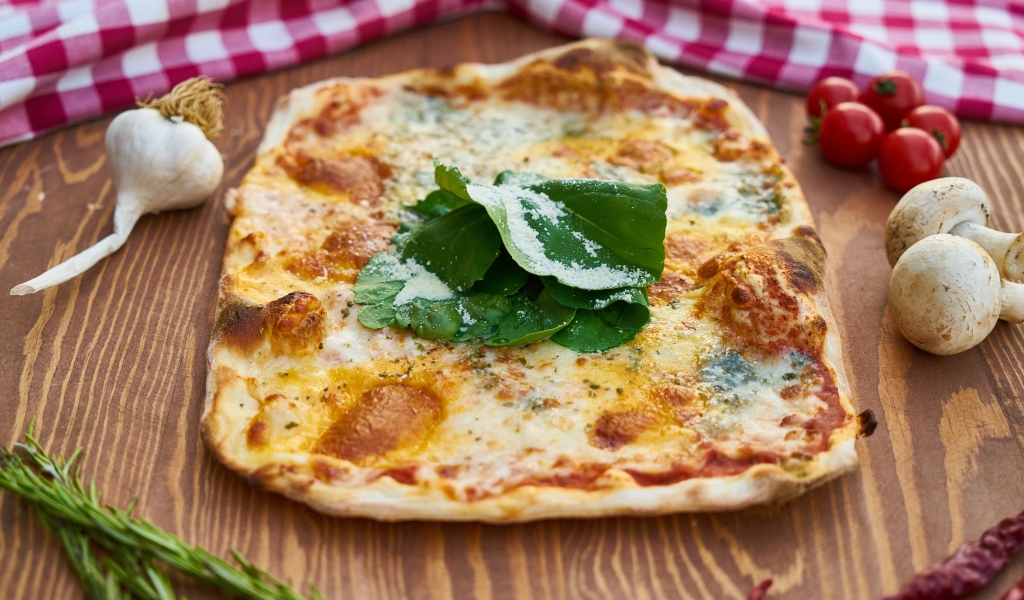 Румяная пицца на столе с овощами