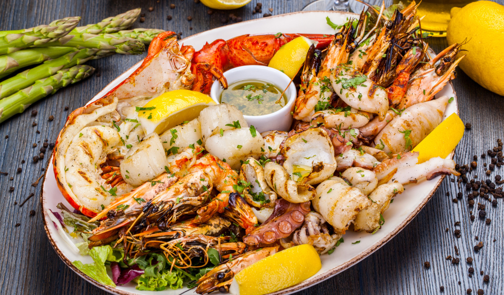 Запеченные морепродукты на тарелке с лимоном 