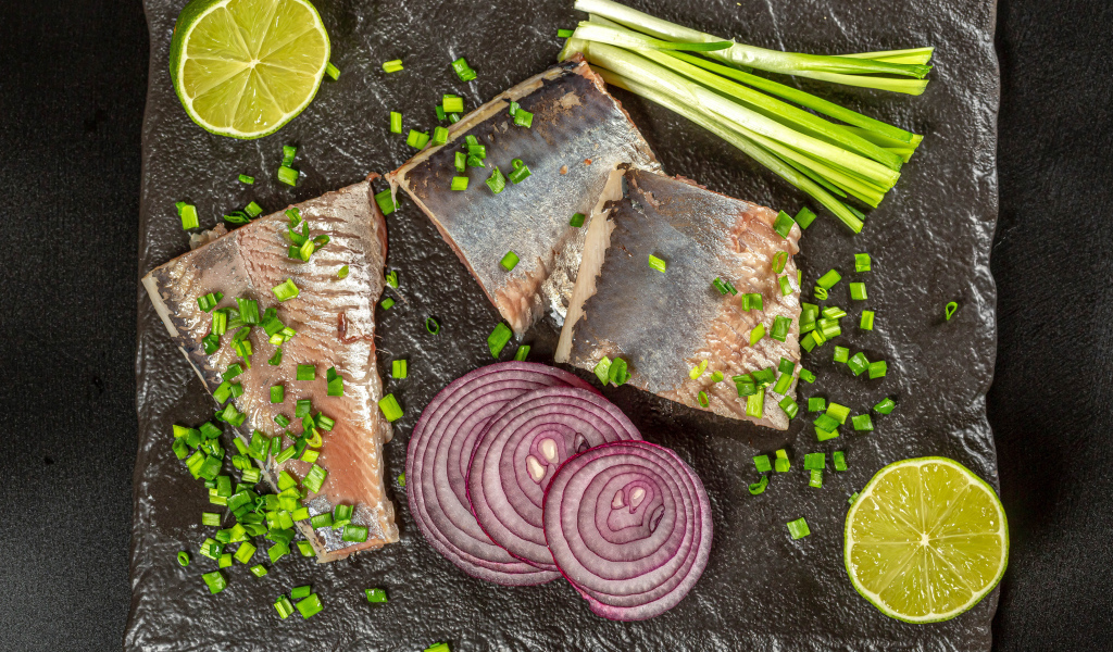 Куски сельди с луком и кусочками лимона