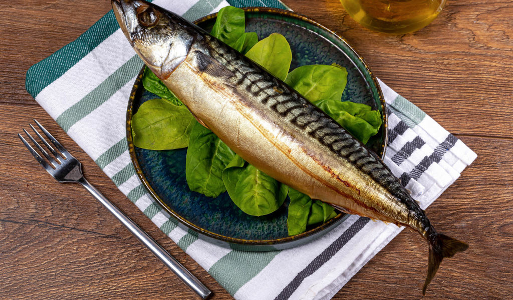 Большая жирная скумбрия на тарелке с базиликом