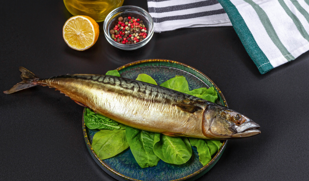 Большая копченая скумбрия на тарелке с базиликом