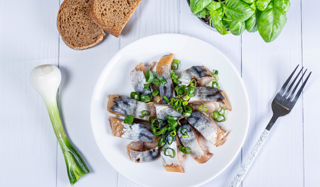 Куски скумбрии на столе с луком, хлебом и базиликом