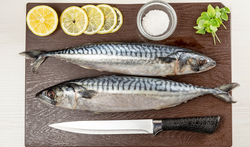 Две свежие скумбрии на доске с лимоном 