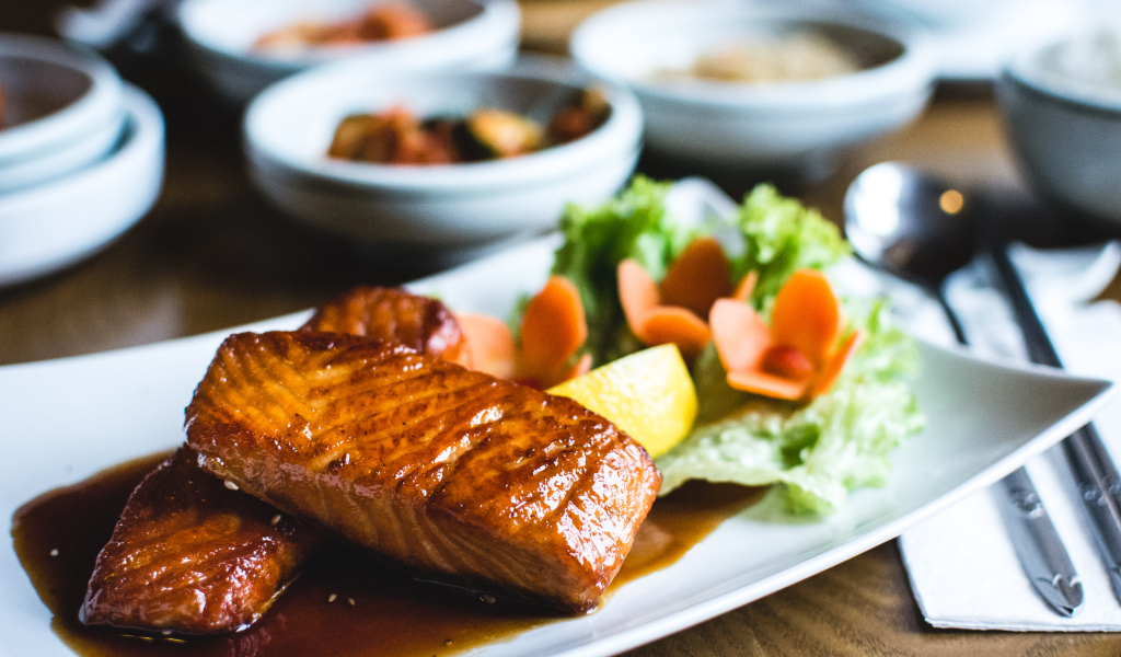 Два куска рыбы в соусе с овощами на тарелке