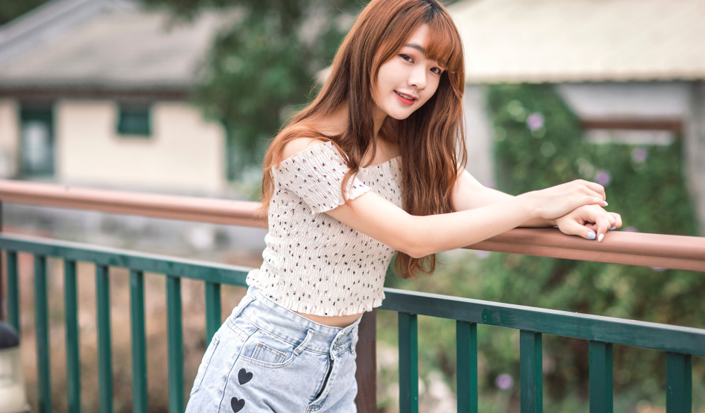 Красивая девушка азиатка стоит у перил у дома