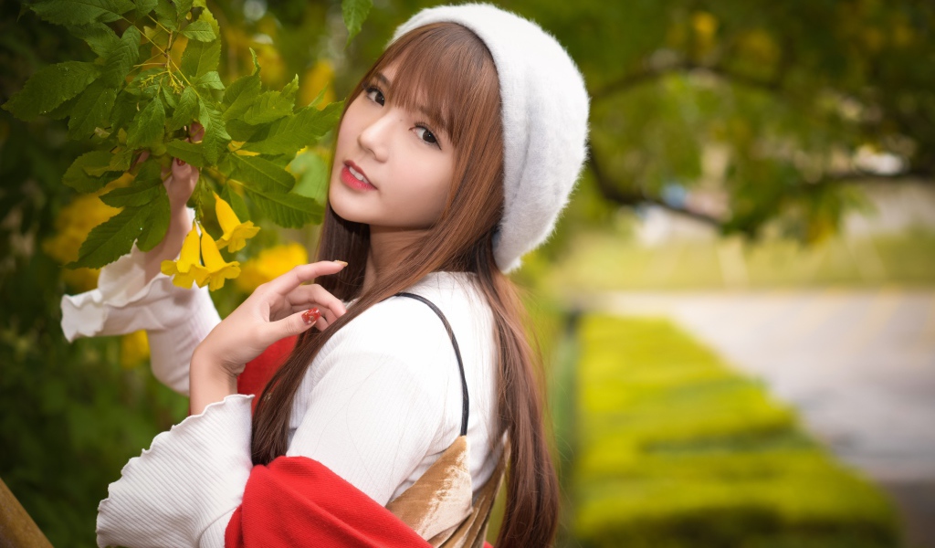 Девушка в берете стоит у куста с желтыми цветами