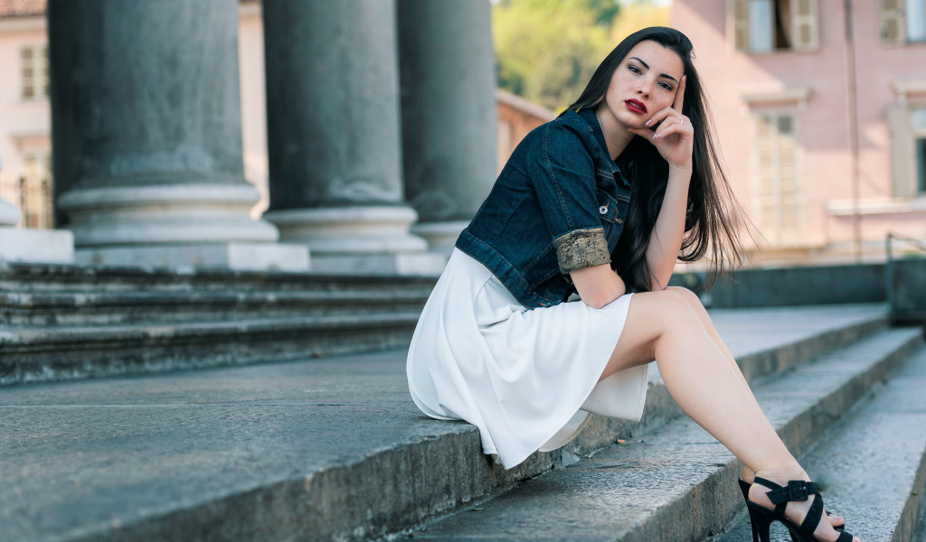 Девушка в белом платье сидит на ступеньках