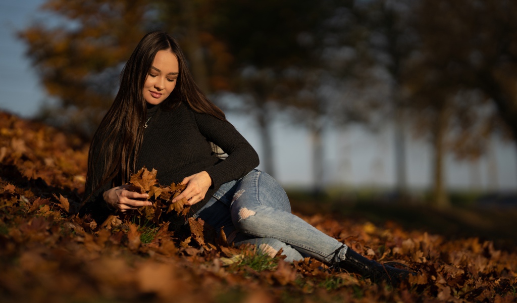 Молодая девушка лежит на опавшей листве