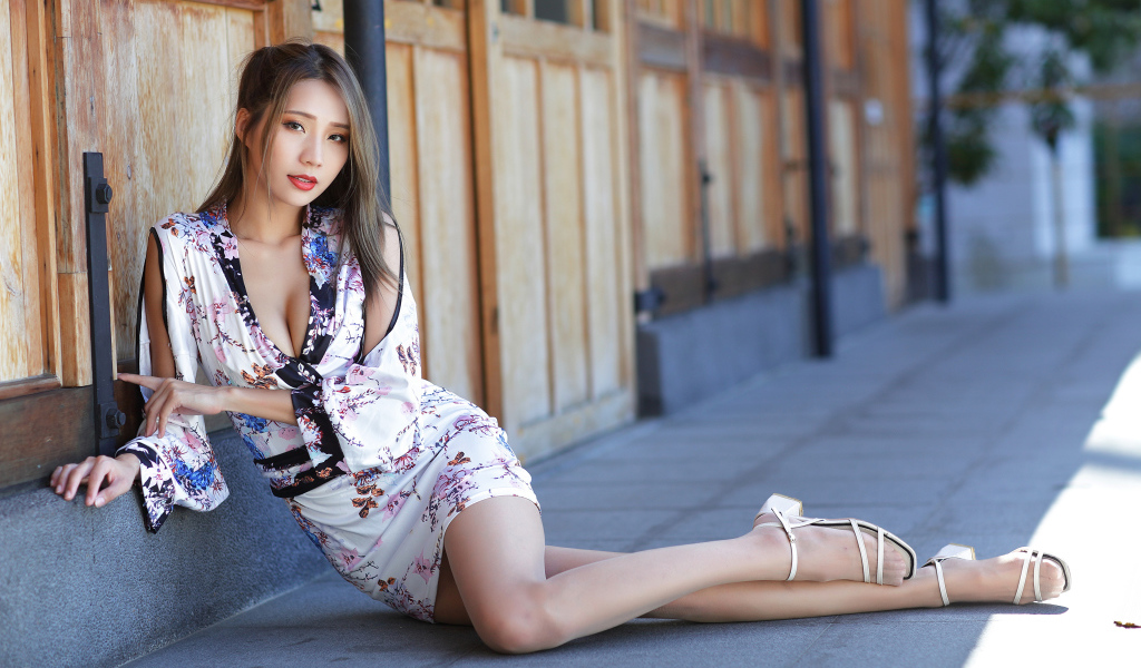 Девушка азиатка в платье сидит на полу у двери