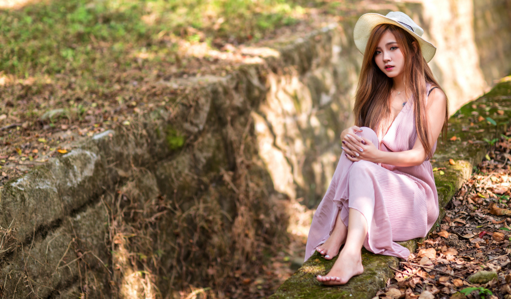 Девушка азиатка в розовом платье сидит на земле