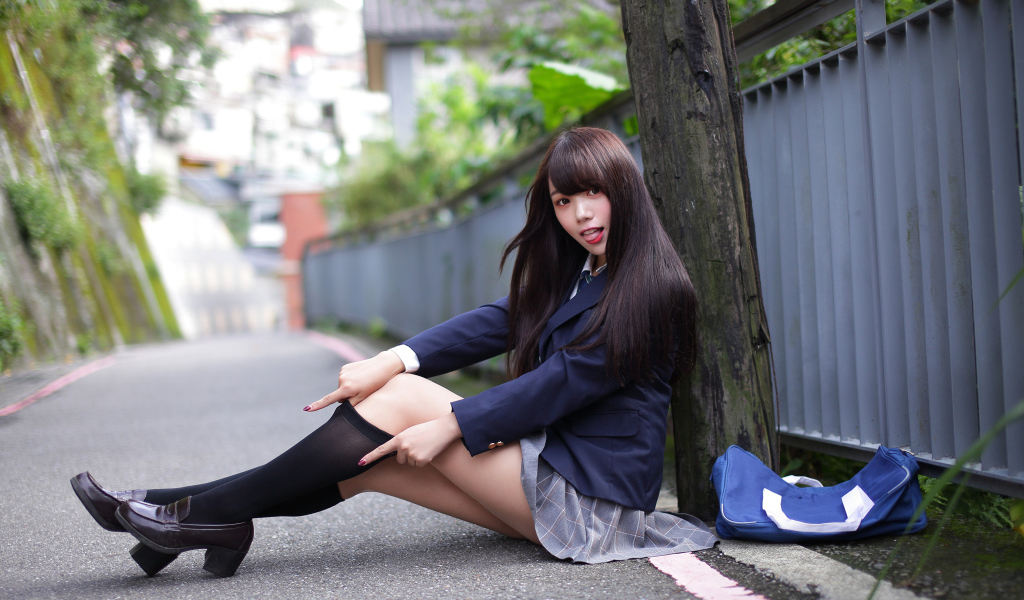 Девушка азиатка в черных чулках сидит у дерева