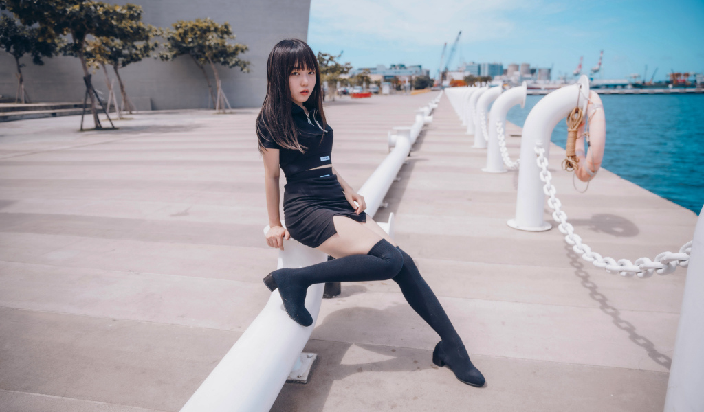 Девушка азиатка в черном костюме на пристани 