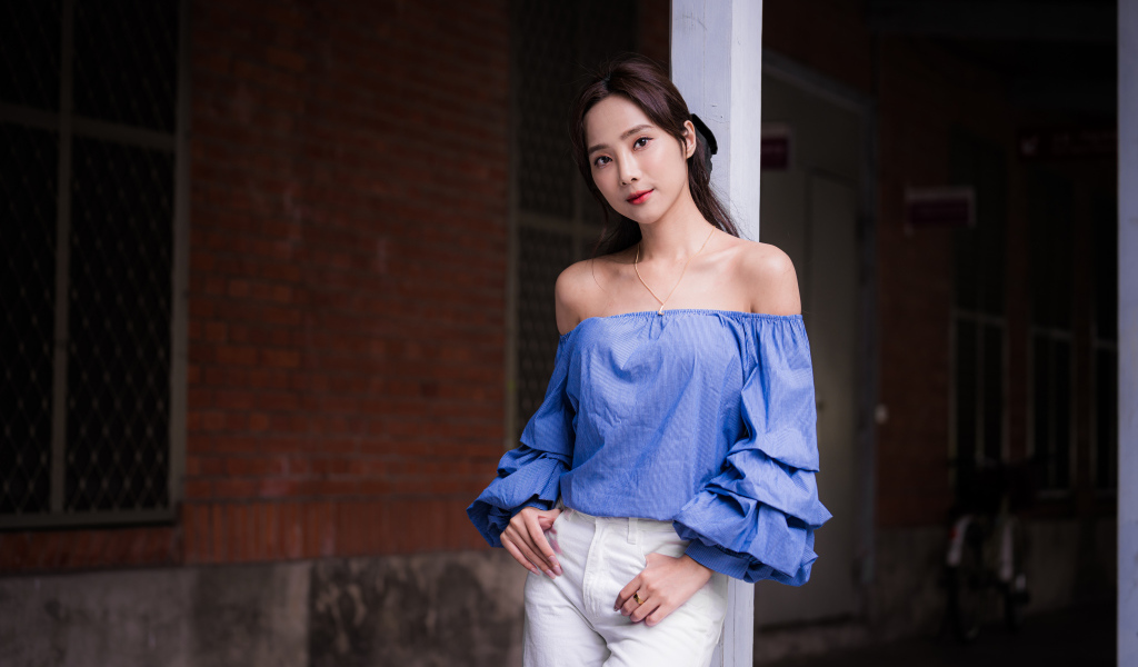 Девушка азиатка в белых брюках у дома