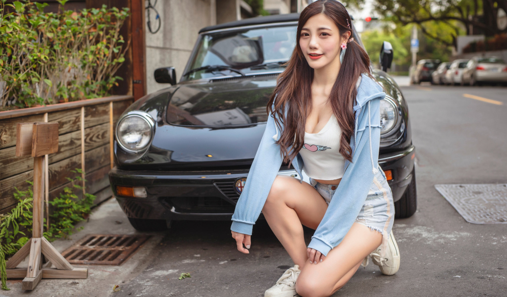 Девушка азиатка сидит возле машины 
