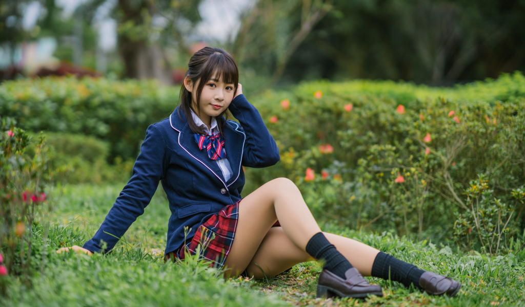 Азиатская школьница сидит на траве