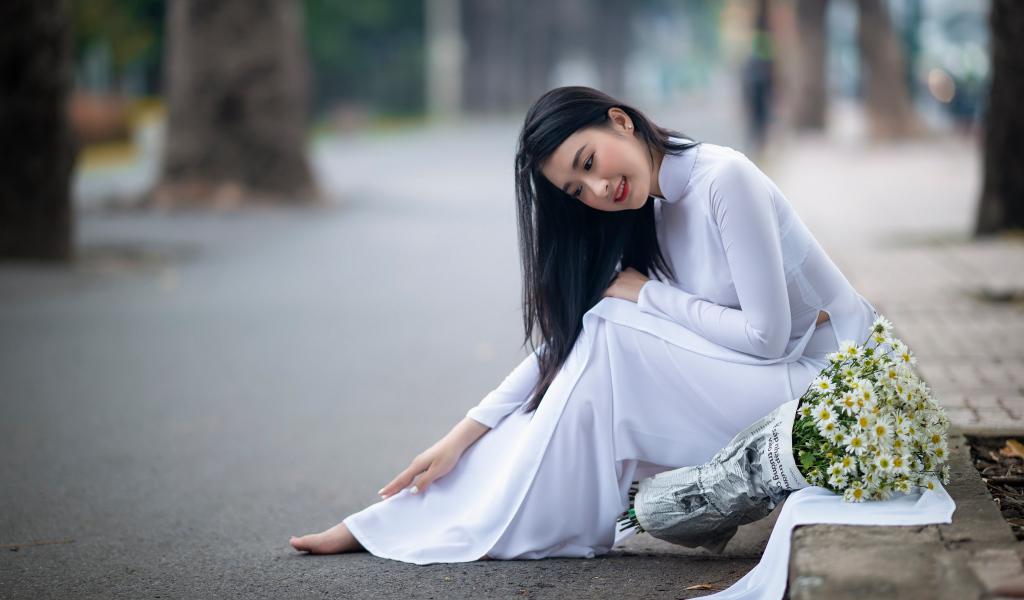 Красивая девушка азиатка в белом платье с букетом ромашек