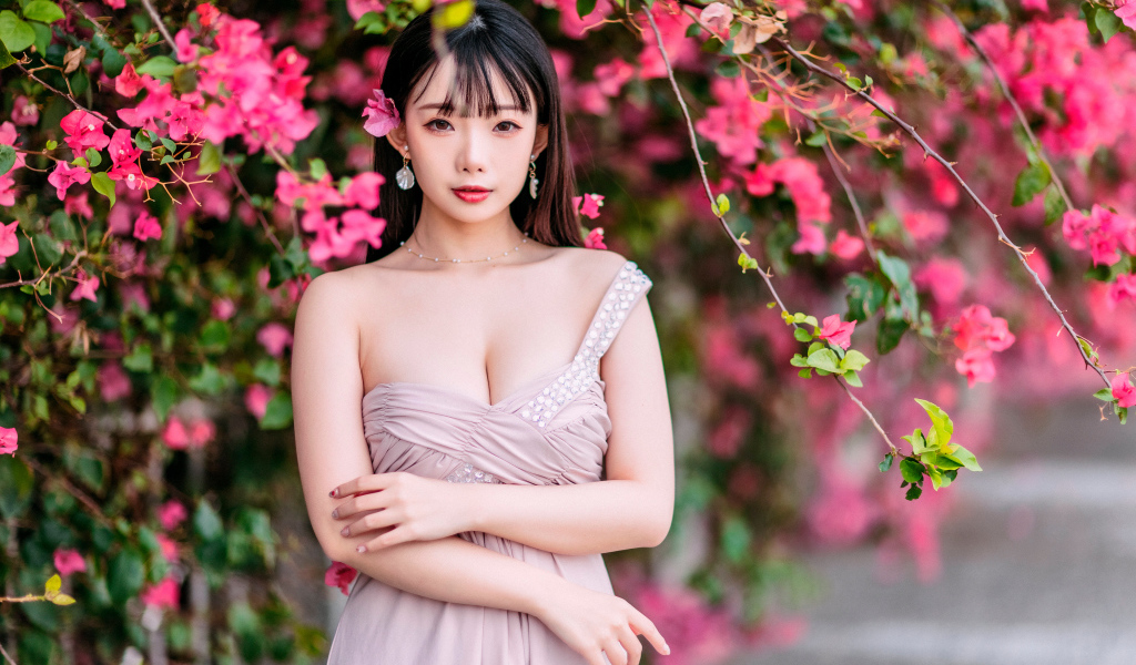 Красивая девушка азиатка у куста с  красными цветами 