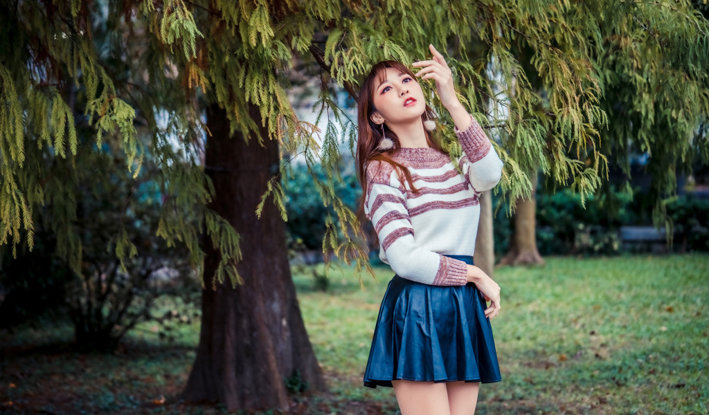 Красивая девушка азиатка стоит у дерева в парке