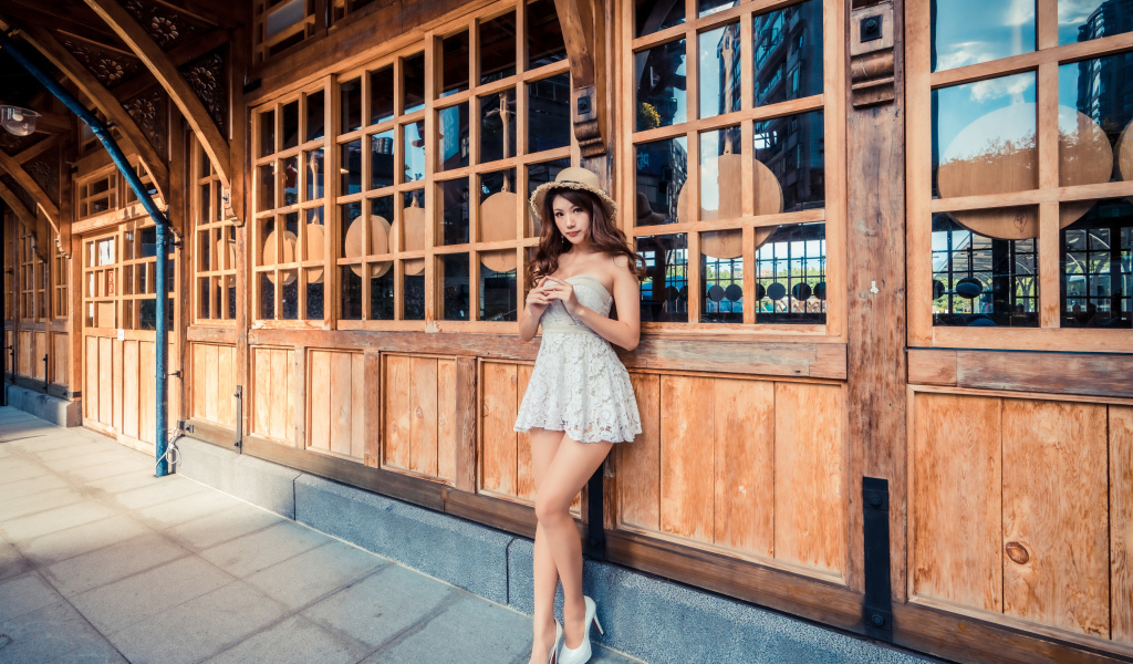 Красивая девушка азиатка стоит у стены с большими окнами